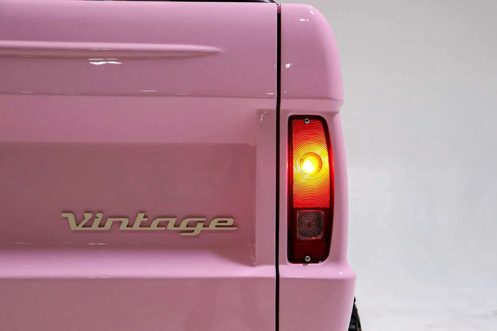 Pink vintage truck tailgate with illuminated taillight detailing.