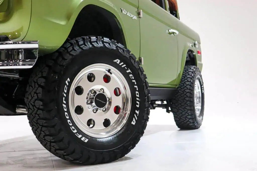 All-Terrain tires on vintage green off-road SUV with chrome accents, showcasing rugged durability and retro-modern style in automotive design.