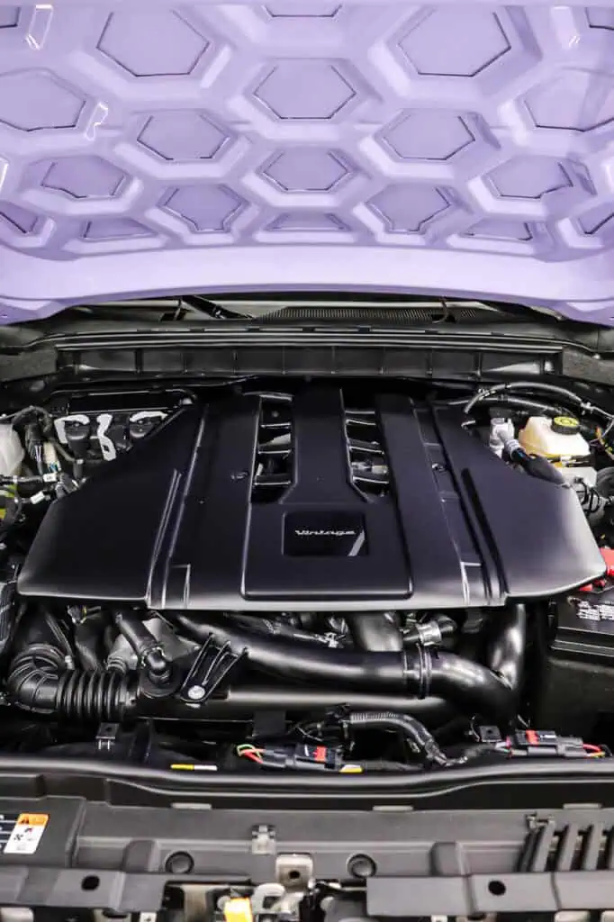 High-performance car engine under a purple geometric-patterned hood, showcasing modern automotive design and powerful engineering details. Perfect for showcasing vintage modern vehicle aesthetics and advanced engine technology.