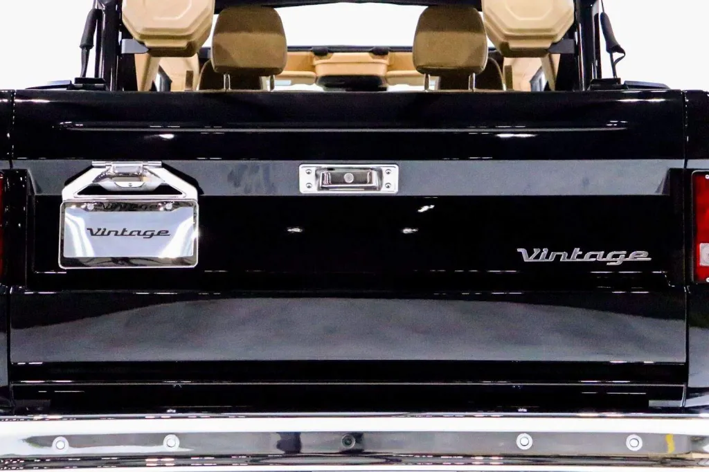 Vintage black golf cart with retro design, featuring beige seats and chrome accents, showcasing vintage modern style.
