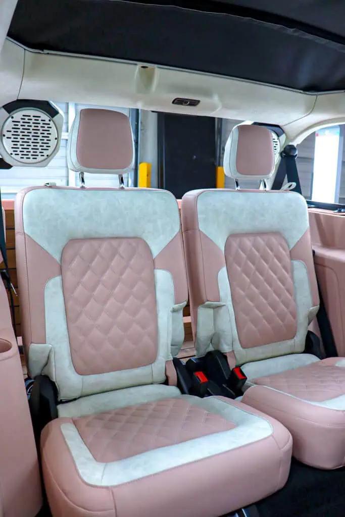 Vintage modern car interior with custom pink and beige quilted leather seats for luxury vehicle.