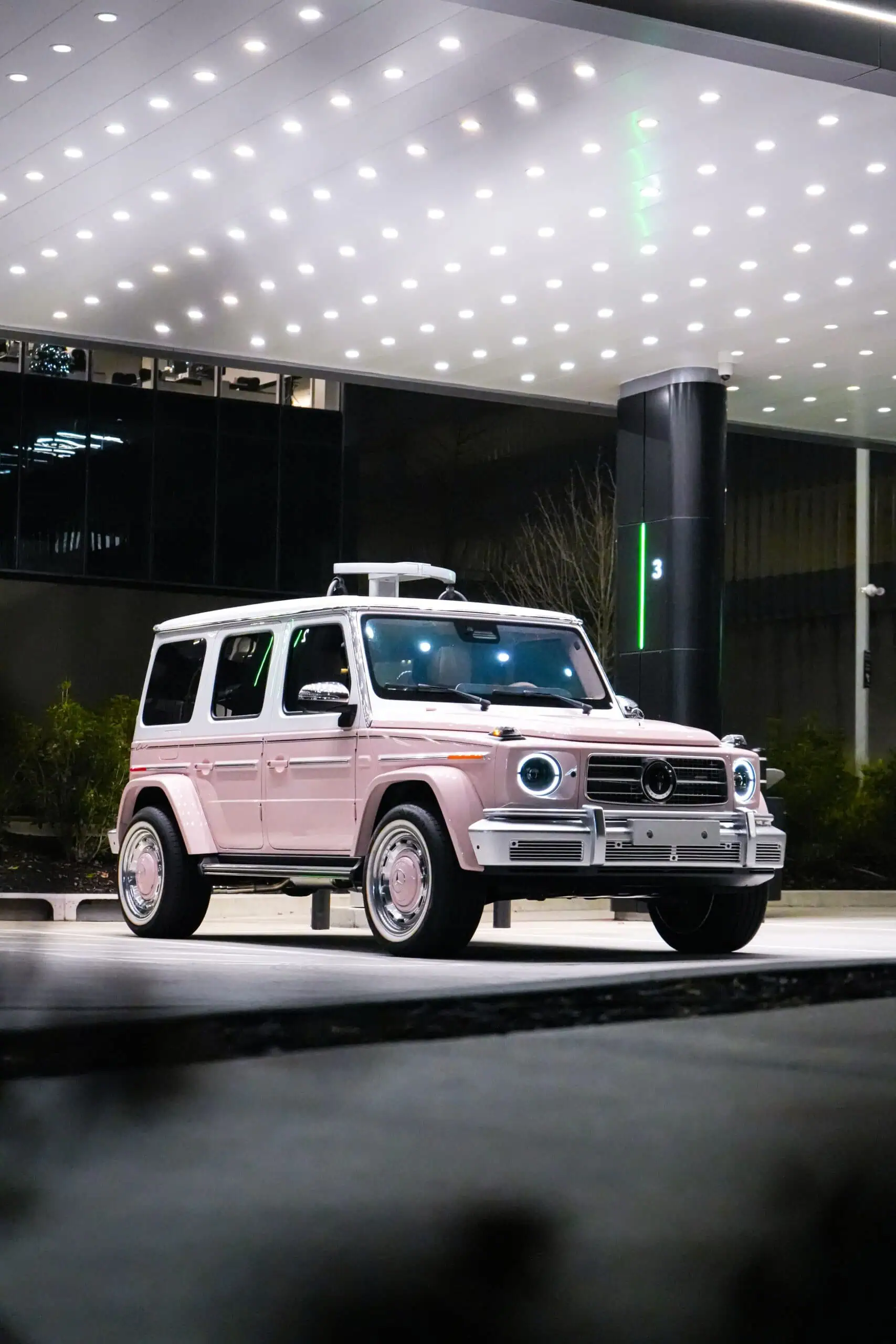 A stylish vintage-inspired Mercedes G-Class SUV parked outdoors at night, illuminated by surrounding modern city lights, perfect for automotive enthusiasts and luxury car lovers.